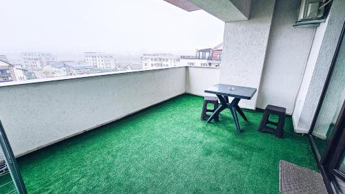a balcony with green flooring and a table and stool at Apartament Dem Radulescu 3 camere! in Râmnicu Vâlcea