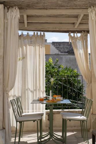 a table and two chairs on a patio with a table and a window at Palazzo Muci in Nardò