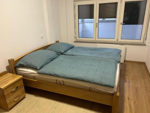a bedroom with a bed with a wooden frame and two windows at Apartman Teo Banja Luka in Banja Luka