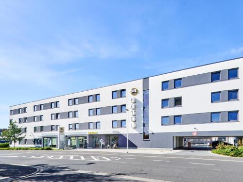 ein weißes Gebäude mit einer Straße davor in der Unterkunft B&B Hotel Aschaffenburg in Aschaffenburg