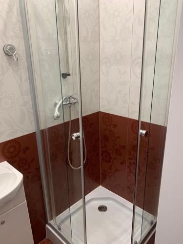 um chuveiro com uma porta de vidro na casa de banho em APARTAMENTY OLIWIA Łeba Bałtycka em Leba
