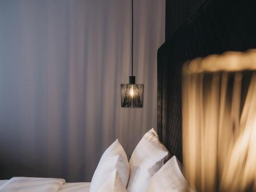 a bedroom with a bed with white pillows and a lamp at The Crystal VAYA Unique in Obergurgl
