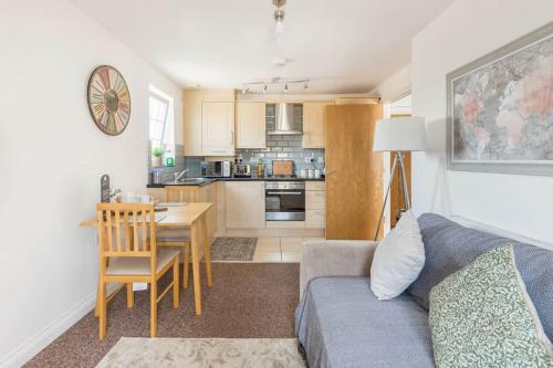 a living room with a couch and a table and a kitchen at Seafront flat- Private parking- Close to town in Weston-super-Mare