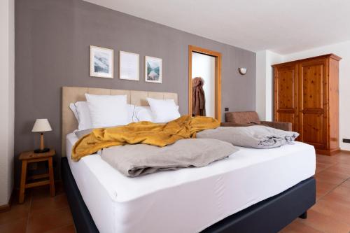 uma grande cama branca com um cobertor amarelo em Chalet Ginepro em Santa Caterina di Valfurva
