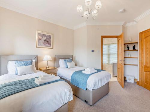 a bedroom with two beds and a chandelier at 2 Bed in Alnwick CN218 in Alnwick