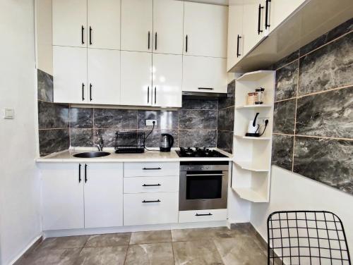 una cocina con armarios blancos y fregadero en Central flat close to the sea fast Wi-Fi, en Antalya