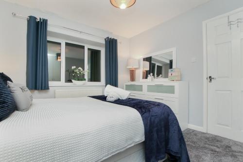a white bedroom with a bed and a mirror at Hurrell House in Boreham