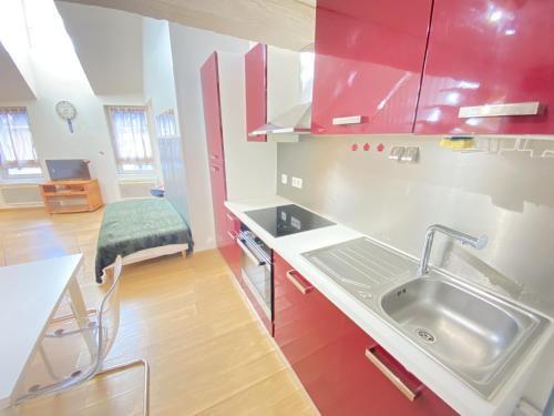 a kitchen with red cabinets and a sink at Le Duplex Ruthenois, Rodez centre in Rodez