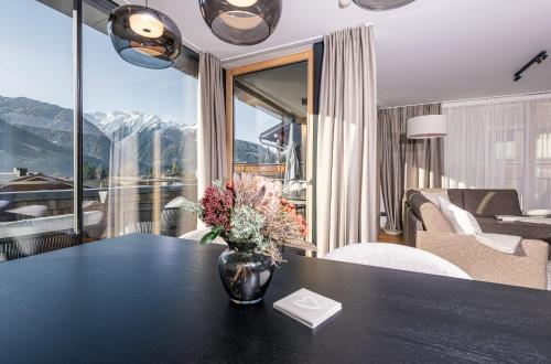 Una habitación con una mesa con un jarrón de flores encima. en Modern Apartment with Panoramic View, en Neukirchen am Großvenediger
