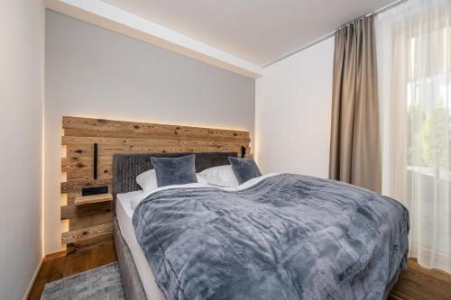 een slaapkamer met een groot bed met een houten hoofdeinde bij Modern Apartment with Panoramic View in Neukirchen am Großvenediger