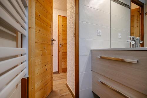 Łazienka z umywalką i drewnianymi drzwiami w obiekcie Les Alpages 73 - Les Saisies w mieście Les Saisies