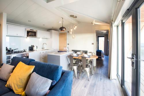 a living room and kitchen with a blue couch and a table at Sauchope Links Holiday Lodge and Glamping Park in Crail