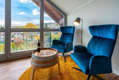 two blue chairs and a table in a room with a window at Weingut Schreieck VINOTEL & GUTSHAUS in Sankt Martin