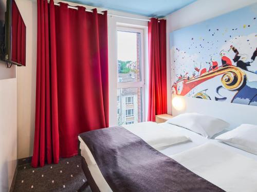 a bedroom with a bed and a window with red curtains at B&B Hotel Mainz-Hbf in Mainz