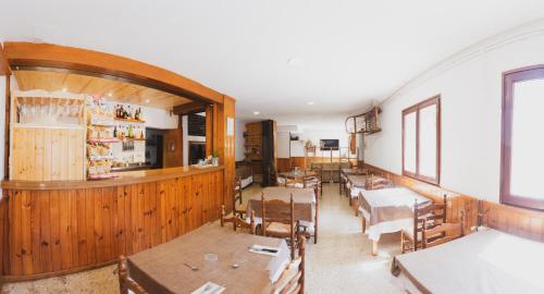 uma sala de jantar com mesas e cadeiras e um bar em Coll de Port em Tuixen