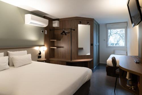 een hotelkamer met een wit bed en een bureau bij Kyriad Nancy Sud - Ludres in Ludres