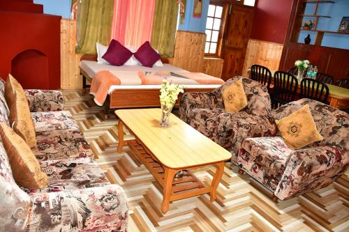 a room with a bed and two couches and a table at Guruchhaya hotel and cottages in Manāli