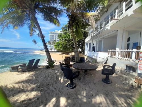 a table and chairs on the beach next to a building at SEASHORE Resort & Villa in Talpe