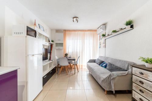 een keuken en een woonkamer met een bank en een tafel bij Apartamento en el centro a un minuto de la playa in Benidorm