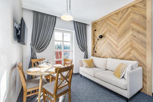 a living room with a white couch and a table at Bukowina Tatrzańska Apartamenty- Tatrzańska 35 blisko termy Bukovina in Bukowina Tatrzańska