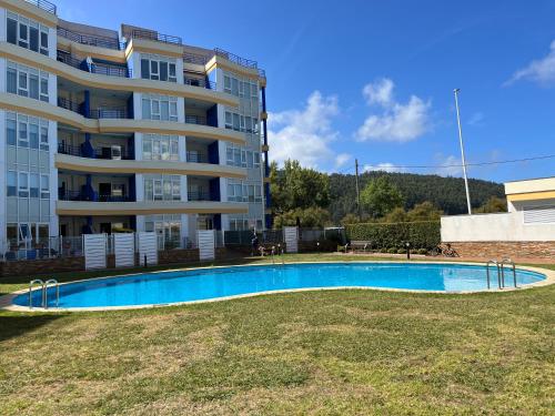 a swimming pool in front of a building at Apartamento con vistas al mar B3 Urb Puerto Azul in Cedeira