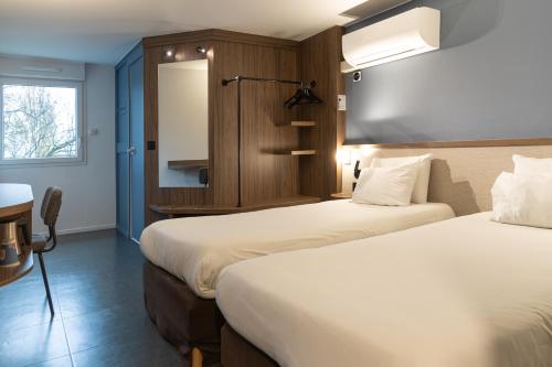 a hotel room with two beds and a window at Kyriad Nancy Sud - Ludres in Ludres