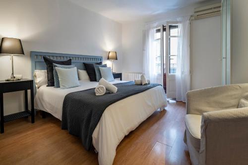 um quarto com uma cama grande e uma cadeira em Habitat Apartments Art em Barcelona