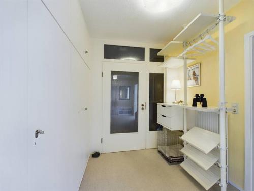 a room with a white room with a shelf and a door at Düne 76 Moderne Ferienwohnung in Baltrum