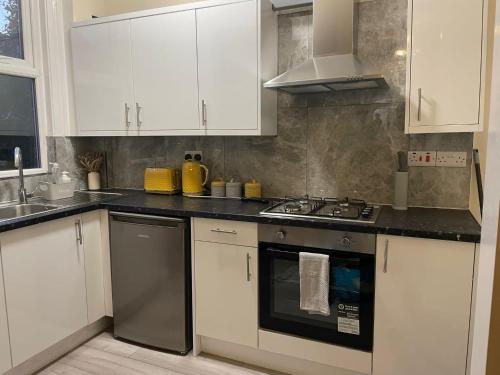 a kitchen with white cabinets and a stove top oven at St James House - Sleeps 8! in Leeds