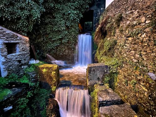 a waterfall in front of a stone wall at Love, made in xisto in Piódão