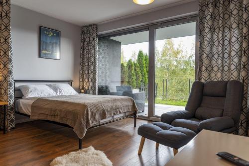 um quarto com uma cama, uma cadeira e uma janela em VacationClub – Bukowa 17A Apartament E.1 em Wisla