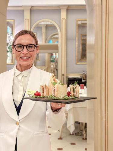 a woman in a white coat holding a tray of food at Hotel Colombina in Venice