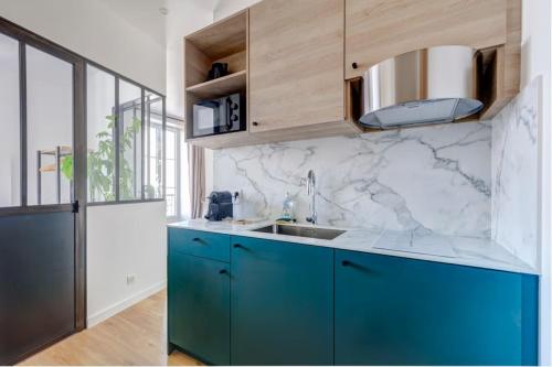 - une cuisine avec des placards bleus et un comptoir en marbre dans l'établissement Le Cosy, centre ville, à Annecy
