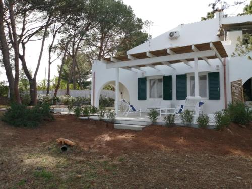 een wit huis met groene luiken en een veranda bij Seaview Villa Lazzaretto in Fertilia