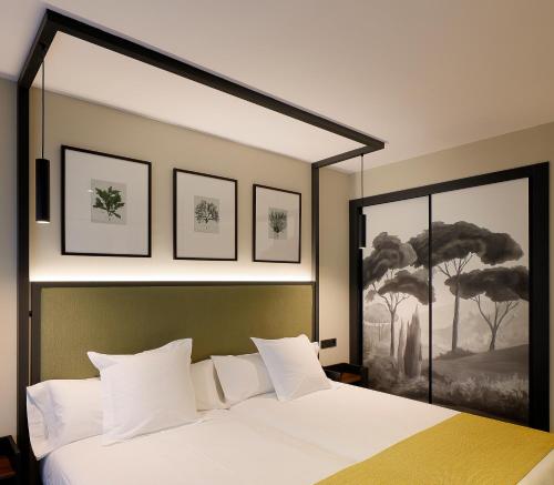 a bedroom with a white bed with three pictures on the wall at Nuvō Hotel Boutique in Oviedo