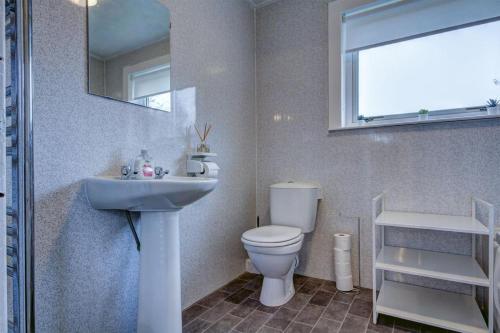 a bathroom with a sink and a toilet and a mirror at Ravenscroft - Coorie Doon in Irvine