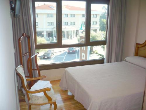 a bedroom with a bed and a large window at Pensión Bos in Bergondo