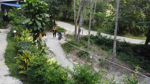 a person walking a dog on a dirt road at Baan Panseng Bungalow in Ko Kood