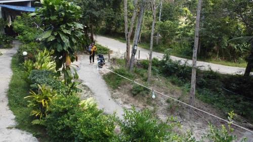 une personne qui promet un chien sur un chemin de terre dans l'établissement Baan Panseng Bungalow, à Ko Kood