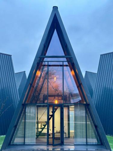 a triangular house with glass windows in front at Green Village Pensiune in Roşu