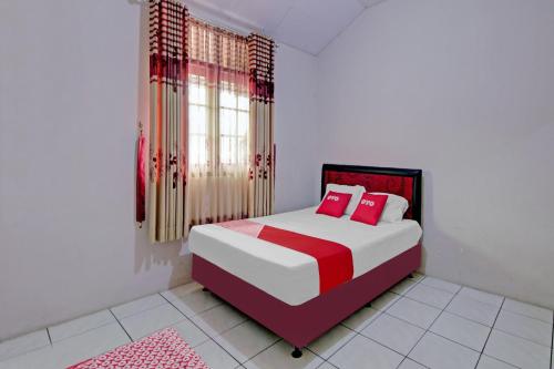 a bedroom with a bed with red and white pillows at OYO 90543 An-nur Guest House Syariah in Kuningan