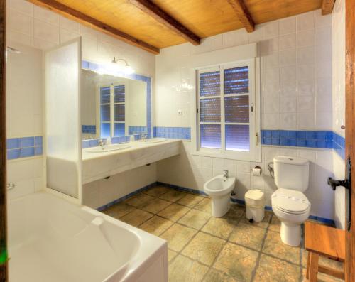y baño con 2 aseos, bañera y lavamanos. en Hacienda los Majadales, en Conil de la Frontera