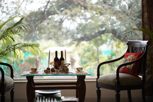 a table with bottles of wine and two chairs in front of a window at Castle Oodeypore A Boutique stay Udaipur in Udaipur