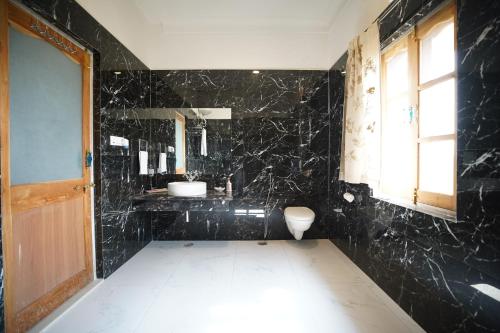 a black bathroom with a sink and a toilet at Castle Oodeypore A Boutique stay Udaipur in Udaipur