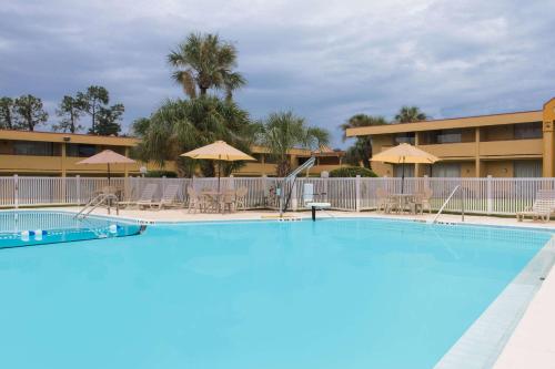 una gran piscina con sillas y sombrillas en Days Inn by Wyndham Ocala North, en Ocala