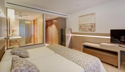 a bedroom with a bed and a desk and a television at Hipotels Gran Playa de Palma in Playa de Palma