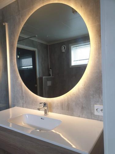 a bathroom with a sink and a round mirror at Apartment with sauna and a sea view in Russenes