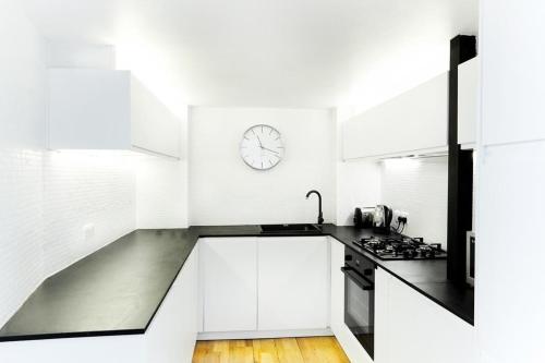 een keuken met witte kasten en een klok aan de muur bij Stylish warehouse- central Brighton in Brighton & Hove