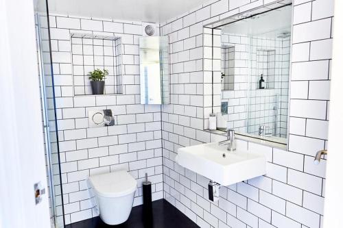 een wit betegelde badkamer met een wastafel en een toilet bij Stylish warehouse- central Brighton in Brighton & Hove