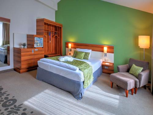 1 dormitorio con 1 cama grande y 1 silla en Mercure Tagungs- & Landhotel Krefeld, en Krefeld